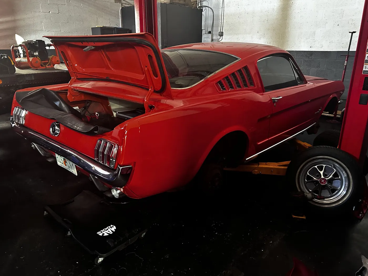 A red classic Mustang inside the Garage 66 service bay